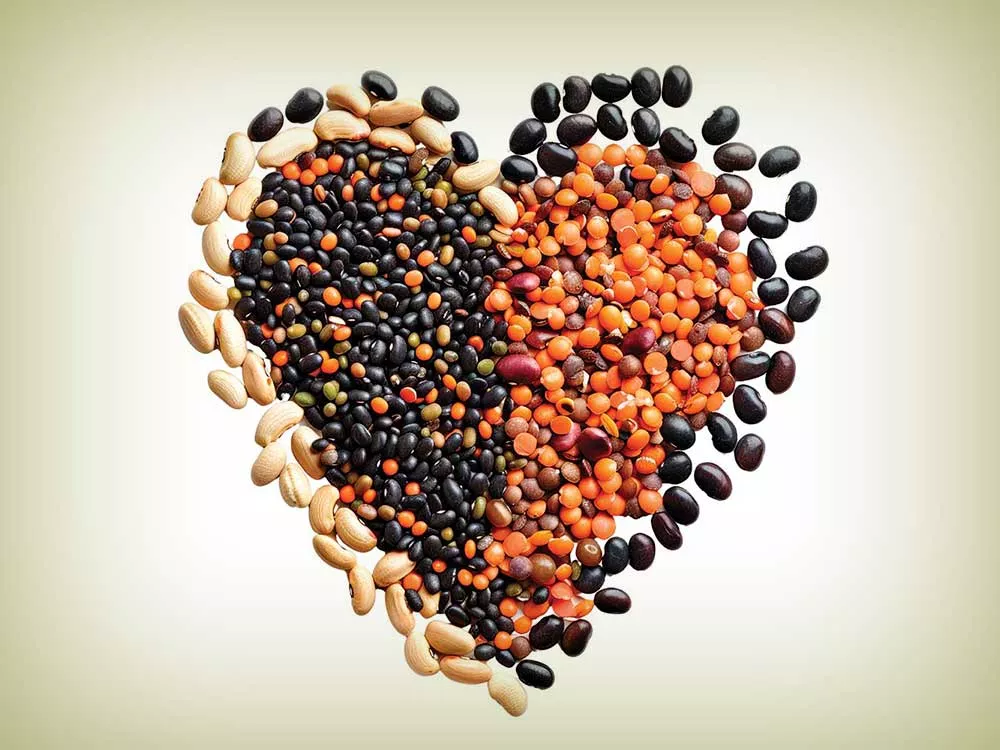 Heart-shaped arrangement of various legumes symbolizing love and nutrition, isolated on a white background, ideal for healthy eating concepts